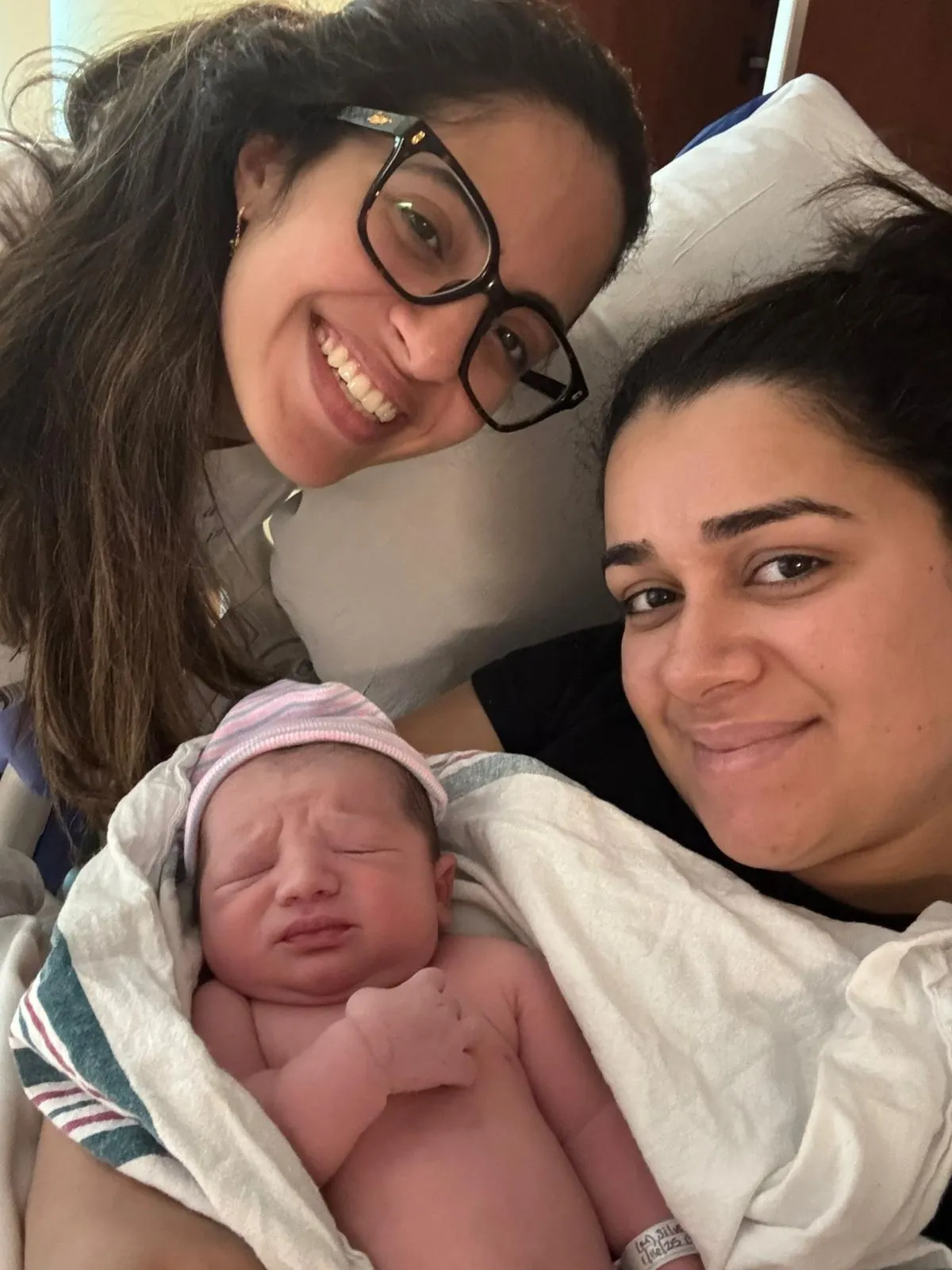 A doula and a new mother smiling with the newborn on the day of the birth